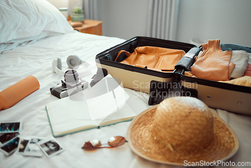 Image of Travel, luggage and bedroom with a suitcase, hat and camera on a bed in a hotel during holiday or vacation. Hospitality, tourist and resort with luggage in a room for traveling or sightseeing abroad