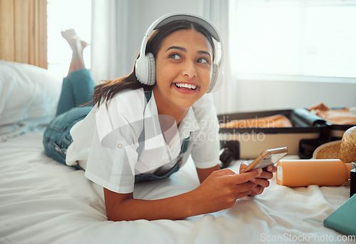 Image of Music, relax and phone with woman and suitcase for travel, summer break and holiday. Technology, headphones and packing clothes with girl on bed of hotel or airbnb for vacation, schedule and booking