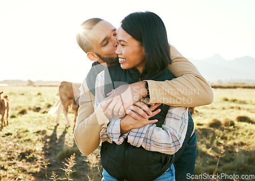 Image of Cow farm, love and couple kiss in the countryside relax on a sustainability farm with cows. Interracial happy couple, summer and marriage smile of people with a hug in nature on a grass field