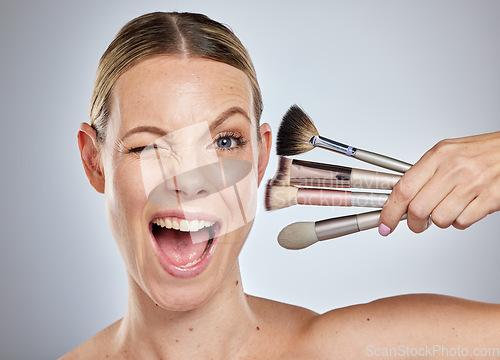 Image of Woman, face and wink with makeup brushes for cosmetics or facial treatment against a grey studio background. Portrait of female model in beauty holding makeup tools in self care or self love