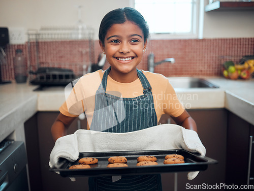 Image of Baking, cookies and children with an indian girl cooking baked goods in the kitchen of her home alone. Food, kids and apron with a female child learning how to bake in her house in the morning