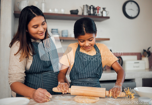 Image of Family, mother and girl baker with a pin rolling dough helping baking a cake, food or cookies in a house kitchen. Child development, learning or happy mom teaching a young Indian kid cooking skills