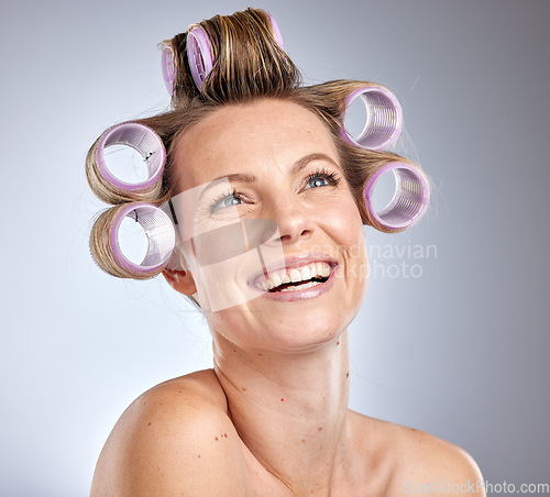 Image of Hair, curlers and thinking with a model woman in studio on a gray background with rollers for hairstyle. Haircare, curling and idea with an attractive young female posing for natural treatment