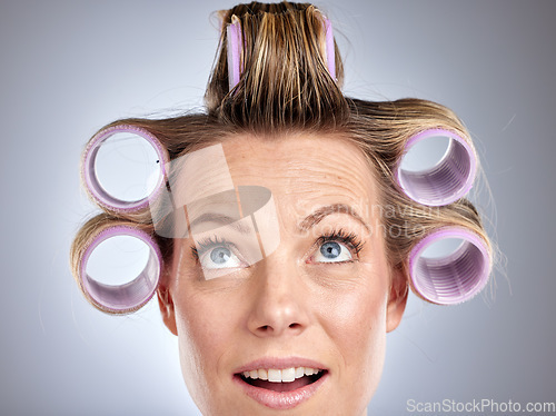 Image of Hair, rollers and beauty with a model woman in studio on a gray background for a hairstyle using curlers. Hair care, thinking and face with an attractive young female styling her curly extensions