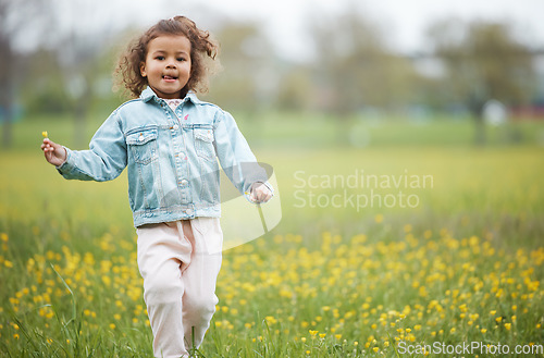 Image of Girl child, field and flower on walk in nature park, garden or backyard for happiness, playing and relax. Young female kid, walking with wild flowers, natural plants or outdoor by trees, grass or sun