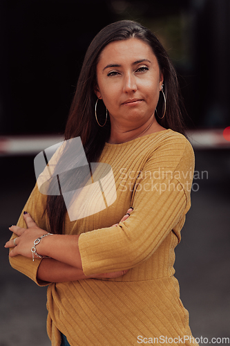 Image of A powerful portrait of a businesswoman, standing confidently with her arms crossed, representing the determination of the female gender and embodying strength and success