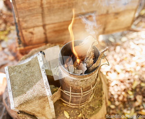 Image of Smoke, fire and metal container on bee farm for agriculture, smoking and honey production. Farming, vintage and beekeeping with flame in smoker to calm bees for safety, protection and preparation