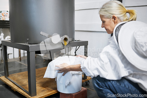 Image of Beekeeper woman, honey production and machine in factory, workshop and organic harvesting process. Apiculture expert, natural product and working with ppe bee suit for manufacturing healthy food