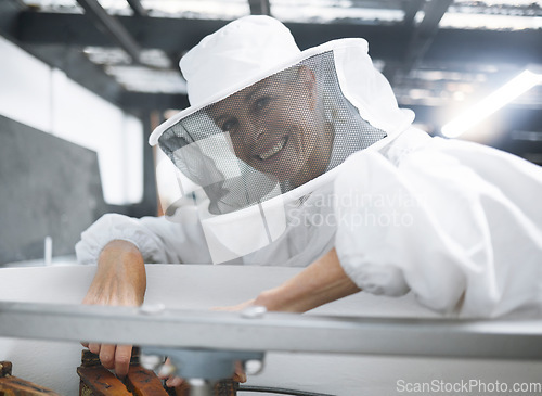 Image of Woman, beekeeper suit and honey production, manufacturing and process in workshop, factory or warehouse. Smile of happy bee farmer for beehive inspection harvest and maintenance of small business