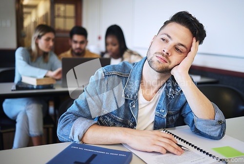 Image of Education, university and bored student in classroom thinking studying for exam. Sad young man at college, boredom and stress, depression or anxiety with book and academic students at desk on campus.