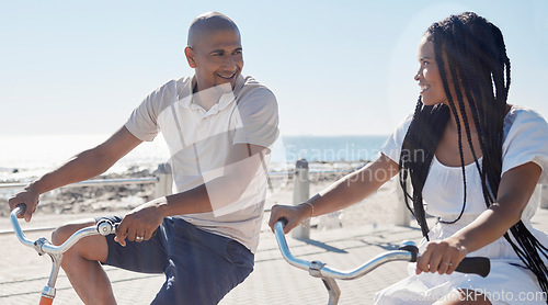 Image of Couple, bike and beach for fun bonding in a happy, loving relationship in Cape Town, Sea Point. Cycling, fitness and bond with a man and woman riding bicycles by the seaside or ocean in summer