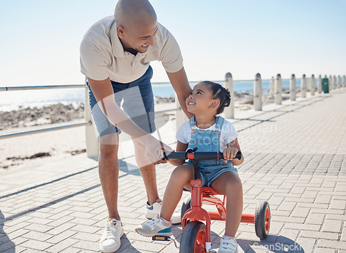 Image of Father, girl child and tricycle at park, learning and happy in ocean sunshine on family vacation. Dad, daughter and happiness by sea promenade, teaching and smile on seaside holiday in San Francisco