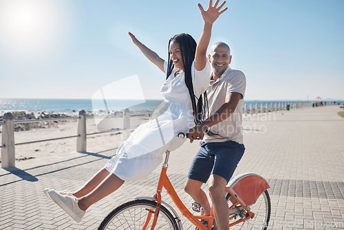 Image of Black couple, bicycle and park by beach, summer and freedom celebration on vacation in sunshine. Happy couple, cycling bike and smile by ocean road for holiday, health and adventure in Miami together