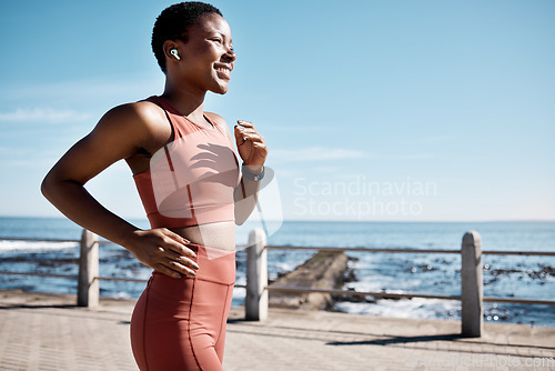 Image of Black woman, music earphone or running by beach, ocean or sea in healthcare wellness or cardiovascular strength. Happy smile, sports runner or listening to workout training or marathon exercise radio