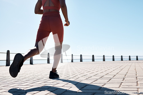 Image of Running, legs and promenade with a sports woman or runner outdoor for an exercise with blue sky mockup. Fitness, workout and shoes with a female athlete taking a run for cardio or endurance training