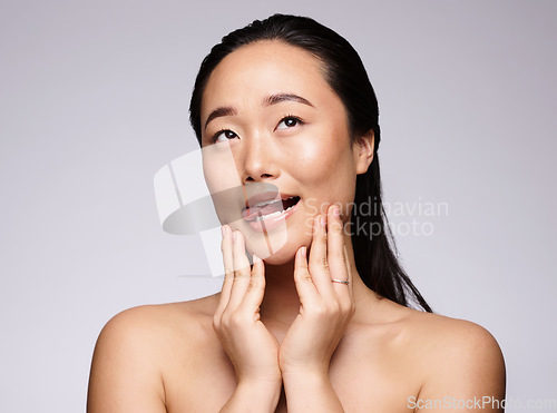 Image of Asian woman, hands and face in beauty skincare for facial cosmetics or treatment against a studio background. Japanese woman smiling with tongue out in satisfaction for hygiene or perfect skin