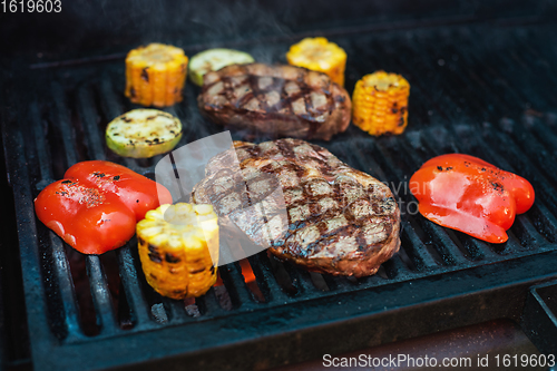 Image of Beef steaks on the grill with flames