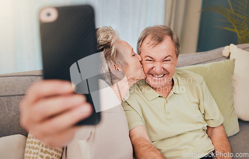 Image of Senior, kiss and phone selfie of a couple with love, care and happiness on a living room sofa. Happy, smile and marriage of a wife and man together on wifi with mobile phone photo for social media