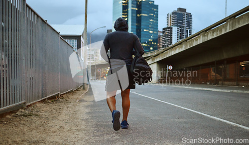 Image of Fitness, black man and walking on city street after running, exercise and gym workout with a hoodie at night. Back of a male athlete in urban Miami for a walk and cardio training with a duffle bag