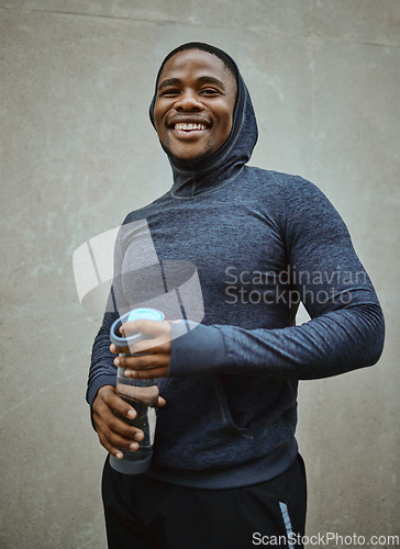 Image of Black man runner, happy and portrait by wall, city and water bottle for health, fitness or wellness. Urban man, smile and happiness for running, training or workout in metro with self care in Chicago