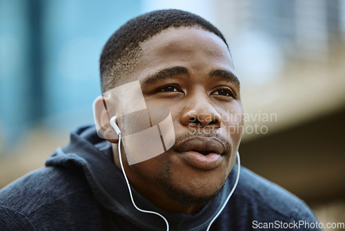 Image of Face, music earphones and black man in city streaming radio or podcast on break after exercise. Sports, fitness and male from Nigeria listening to workout song while thinking of running in winter.