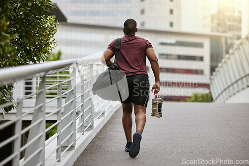 Image of Fitness, city or black man walking to gym on a bridge with a sports bag or water bottle for a workout or exercise. Back view, motivation or healthy person traveling to a training center or club