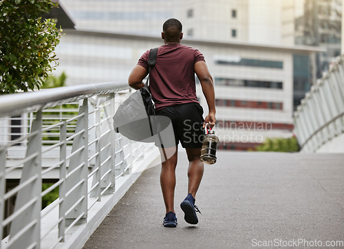 Image of Fitness, health and man walking to gym with bag and water bottle ready for training or exercise workout. Motivation, bodybuilding and sports, strong black man athlete on street in city with gym bag.