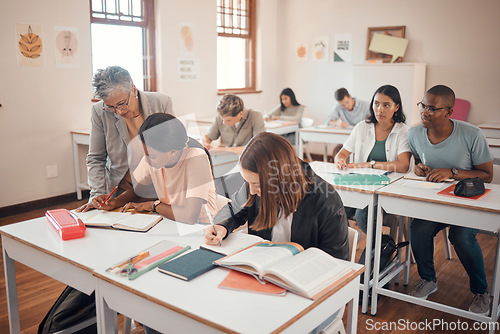 Image of School, students and classroom with teacher help, answer and explain during lesson with young group. Education, study and elderly woman teaching, checking and showing and helping pupil textbook exam