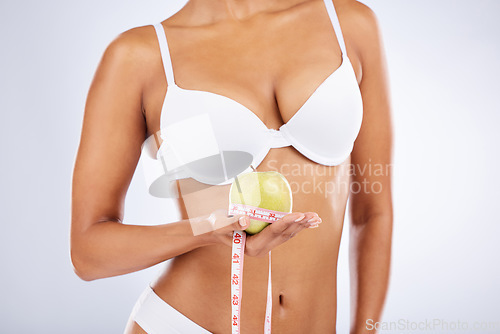 Image of Apple, tape and woman underwear in studio with diet, lose weight results and body goals for wellness, healthcare and nutrition. Fruit, nutritionist and model in lingerie with gut health and digestion