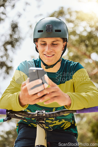 Image of Mountain bike, phone and man outdoor in nature forest while online with a smile for communication or watching stunt video on internet. Athlete male with bicycle and smartphone for sports training