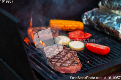 Image of Beef steaks on the grill with flames