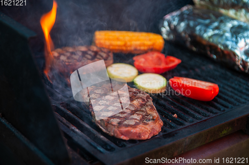 Image of Beef steaks on the grill with flames