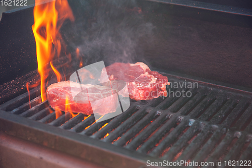 Image of Beef steaks on the grill with flames