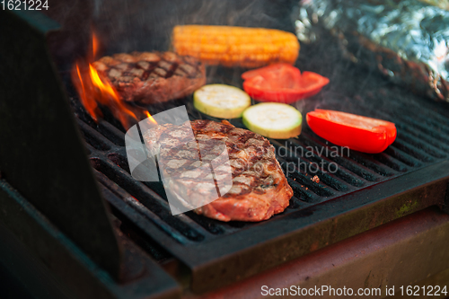 Image of Beef steaks on the grill with flames