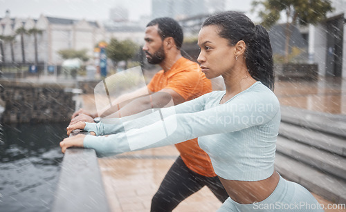 Image of Workout, stretching and couple of friends training with focus before running in the rain. Urban, runner athlete and sports exercise in winter of black people with motivation in the city for fitness