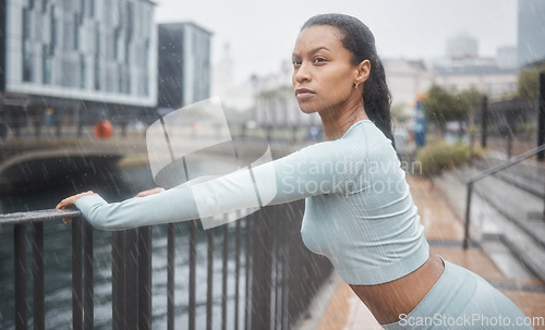 Image of Workout, stretching or black woman runner training for mindset focus running in the rain. Wellness, health athlete and sports exercise in winter of girl for motivation in the city for fitness warm up