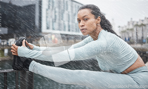 Image of Fitness, rain or black woman stretching in city of London to start running exercise, workout or cardio training. Portrait, mindset or healthy girl athlete runner in sports warm up on a street or road