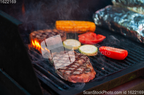 Image of Beef steaks on the grill with flames