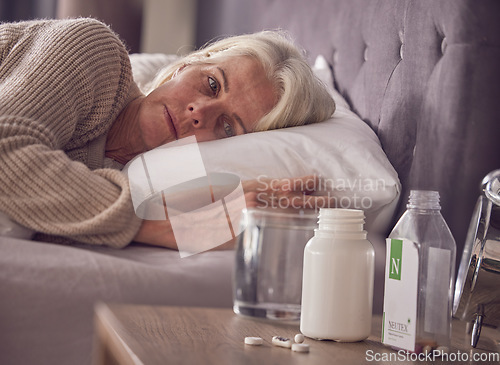 Image of Elderly woman, bed and medical addiction with pills, medicine or medication while lying awake at home. Senior female suffering from sick, illness or mental health, trauma or disorder in the bedroom