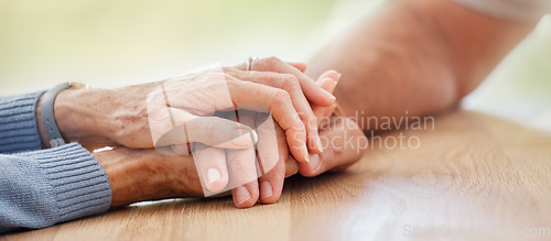 Image of Senior, holding hands and support with couple, comfort and help on table for grief, pain or sympathy. Elderly man, old woman and helping hand for empathy, love and care in home with bonding together