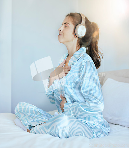 Image of Woman, morning and headphones for meditation on bed while listening to music or podcast while breathing for chakra exercise in bedroom. Female at home with pajamas with audio for mental health