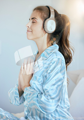 Image of Headphones, prayer or woman in meditation in bedroom streaming relaxing zen music, yoga podcast or radio at home. Morning, peace or calm spiritual girl praying for mindfulness, health or wellness