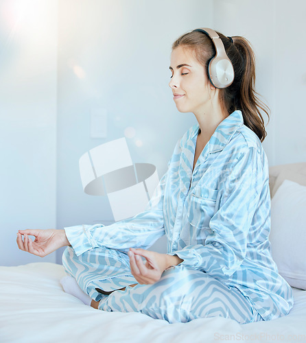 Image of Yoga, meditation or zen woman in bedroom with headphones streaming relaxing radio, calm music or podcast. Peace, mental health or spiritual girl in lotus pose to meditate for mindfulness or wellness