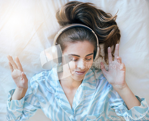Image of Woman, headphones and music, listening in bed to relax at home, podcast or radio streaming, peace and satisfaction. Young, wellness and positivity in bedroom, mindset and self care listen and freedom