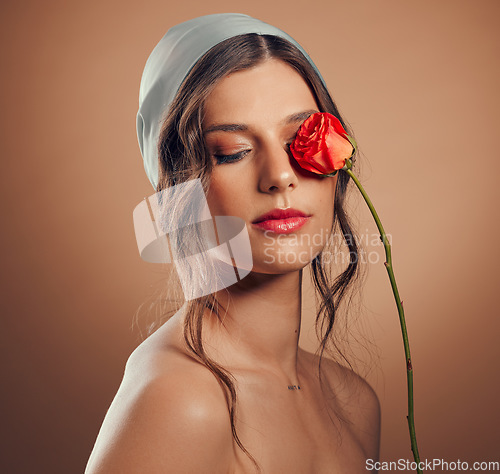 Image of Flowers, thinking and woman with makeup beauty, floral wellness and creative on a brown studio background. Peace, flower and model with a rose for creativity, luxury aesthetic and idea for cosmetics