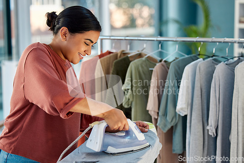 Image of Designer woman, iron clothes and smile in boutique, store or workshop with focus, vision and clothes rack. Fashion clothing expert, factory or studio with fabric, ironing or vision for design startup