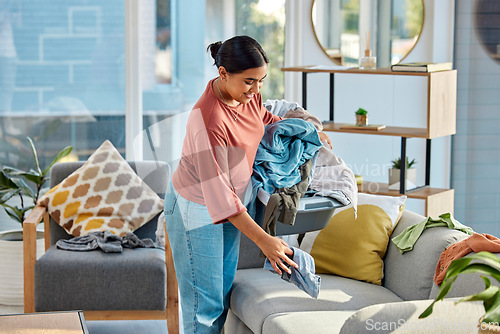 Image of Woman, laundry and house for cleaning, happy and fresh scent in living room. Latino female, maid and cleaner with chores, clothes and smile for housekeeping, home and clean in lounge for household.