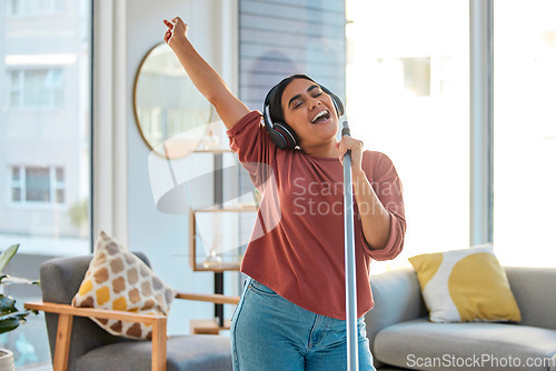 Image of Music, headphones and woman singing while cleaning home, dancing and having fun. Singer, dance and female spring cleaning for hygiene holding broom like microphone, sweeping dust and streaming radio.