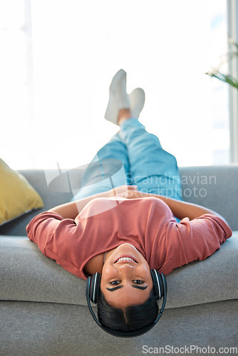 Image of Woman, sofa and upside down with headphones, smile or music in portrait to relax in lounge. Happy lady, couch or audio for happiness, streaming podcast or internet radio in home living room in Mexico