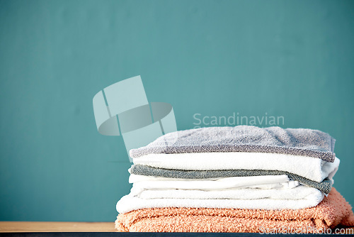 Image of Bathroom, laundry and stack of towels on blue background for cleaning, washing and body hygiene at home. Fabric, textiles and pile of fresh, soft and clean linen for shower, bath and spa wellness